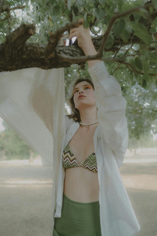 a girl is posing underneath a tree with white and green outfits