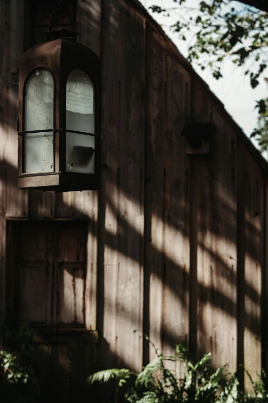 an old red shed has an old fashioned light fixture hanging from it