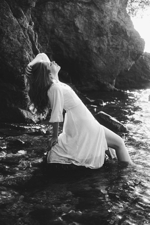 a  kneeling in a body of water on the beach