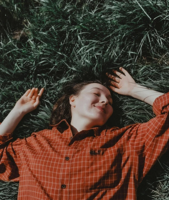 the young man laying in grass is smiling at soing