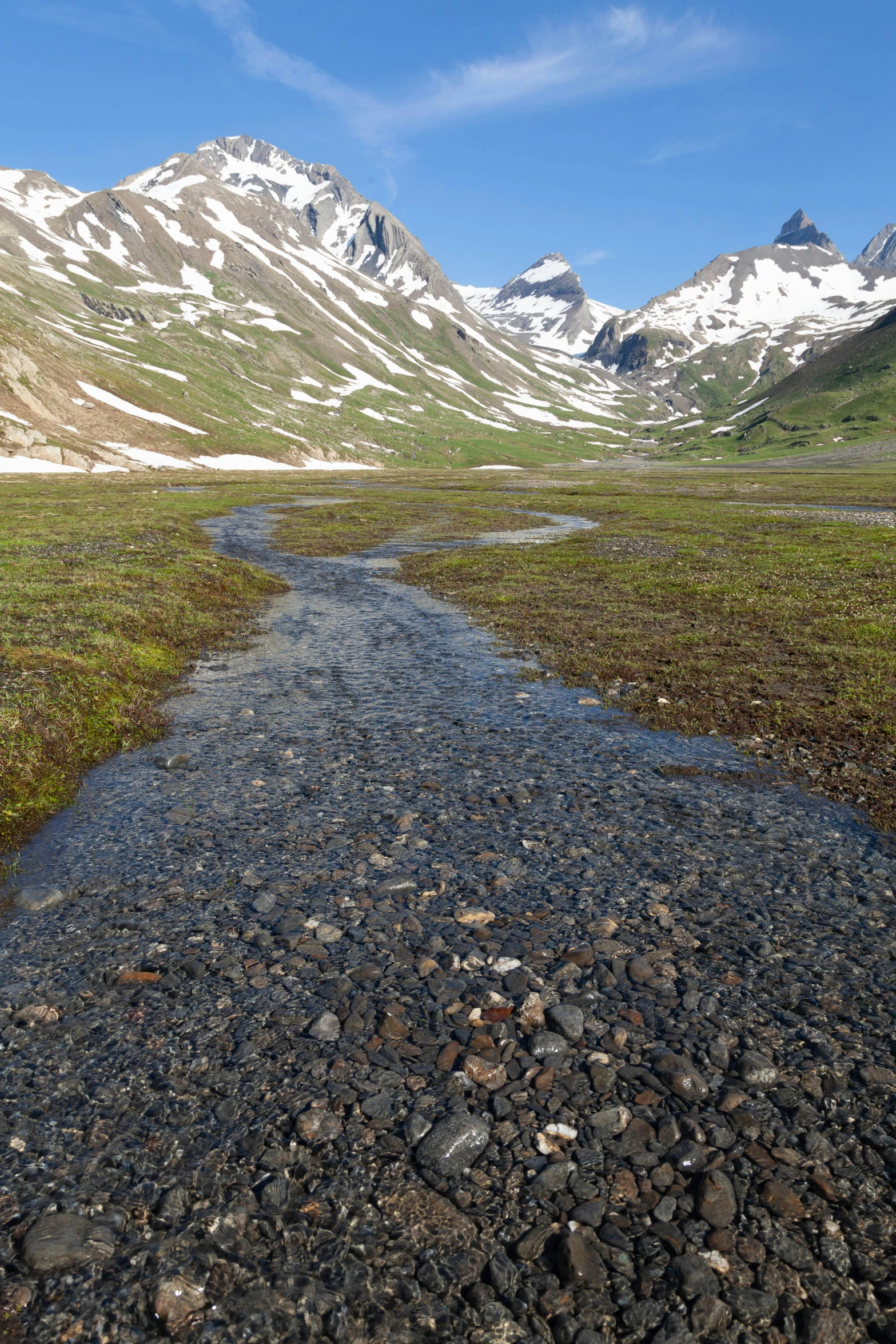 the mountains are covered with snow and green grass