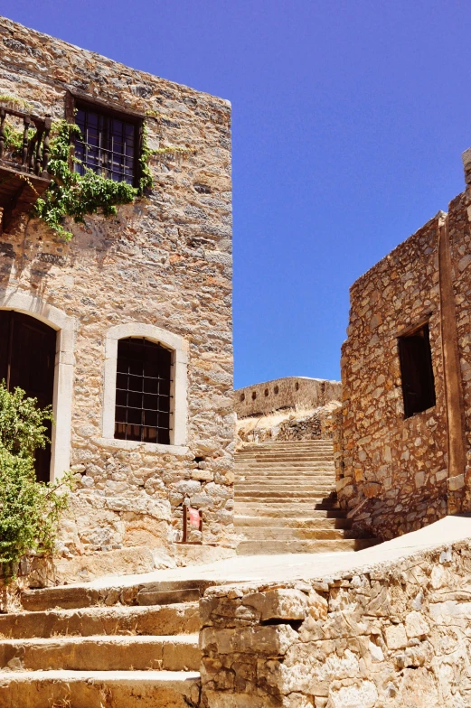 the stairway in front of the stone building has stairs with windows