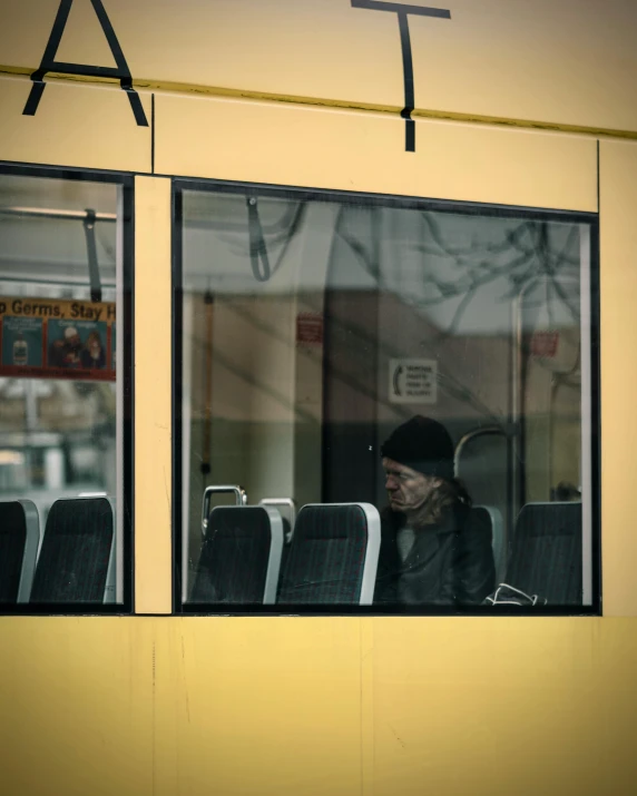 a woman sits looking out the window of a bus