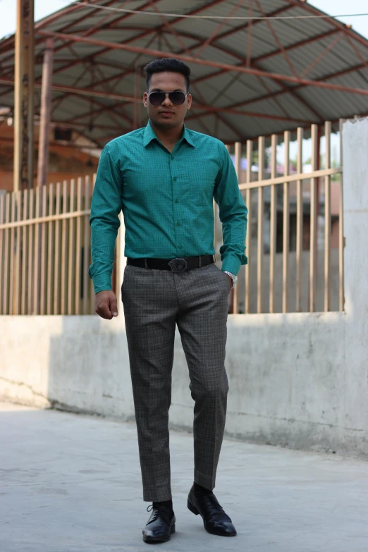 a man standing in a green shirt and a black suit pants