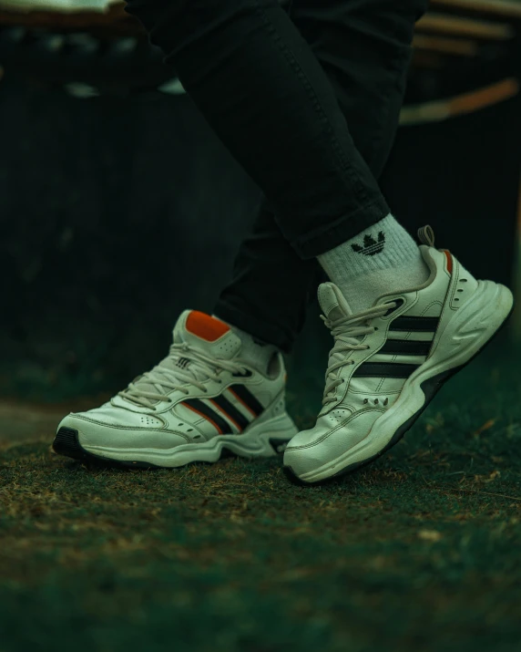 the sneakers of a man standing in front of a bench