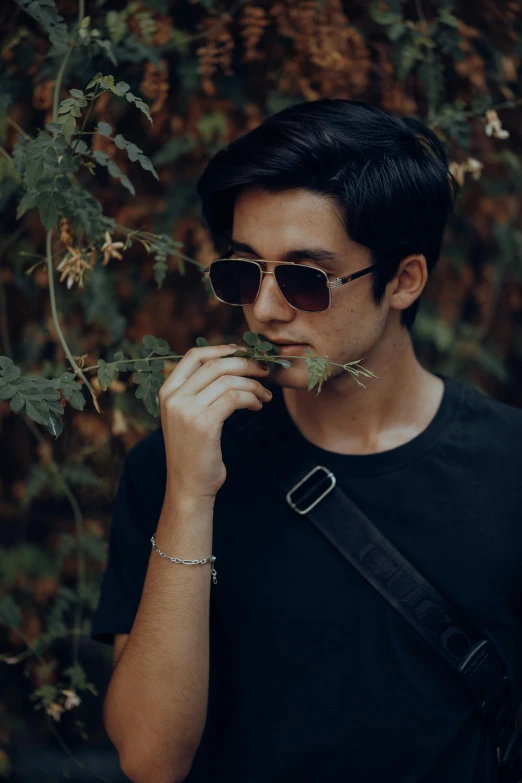 a man with glasses holds a plant in his mouth