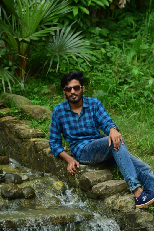 an indian guy sitting in the middle of a water fall