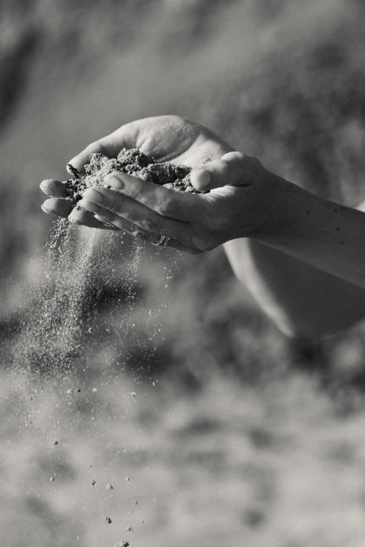 someone holding their hands in sand outside