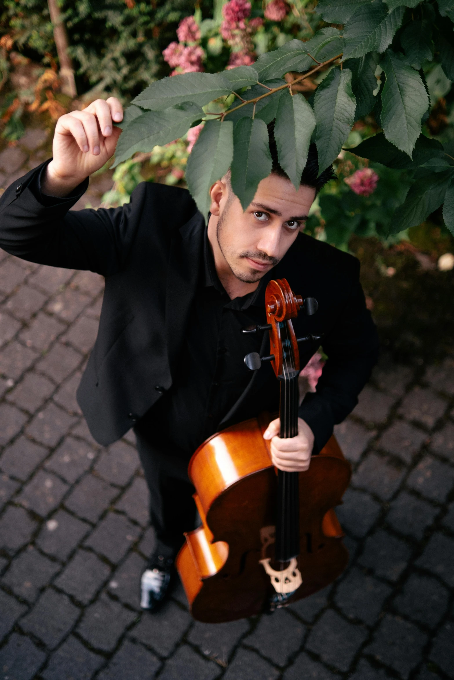 man in black suit holding violin and posing for po