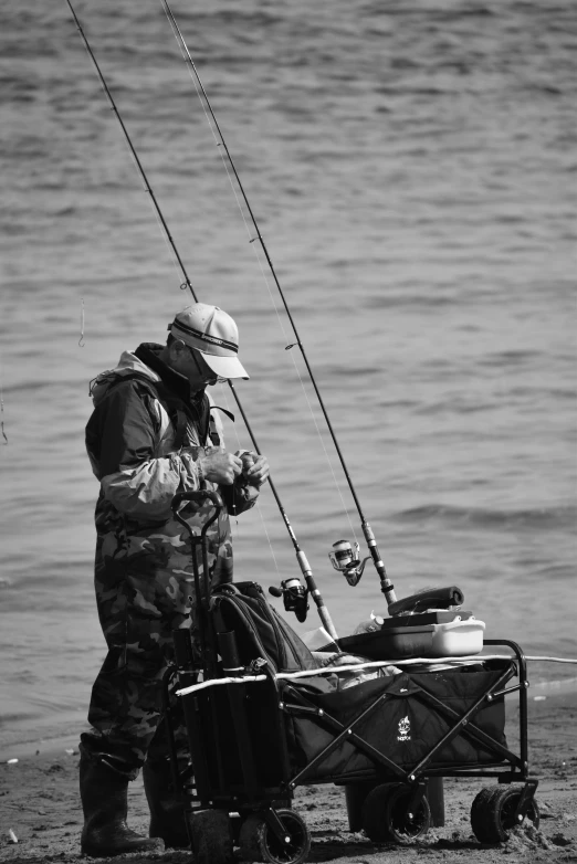 fisherman on beach near body of water holding onto rod