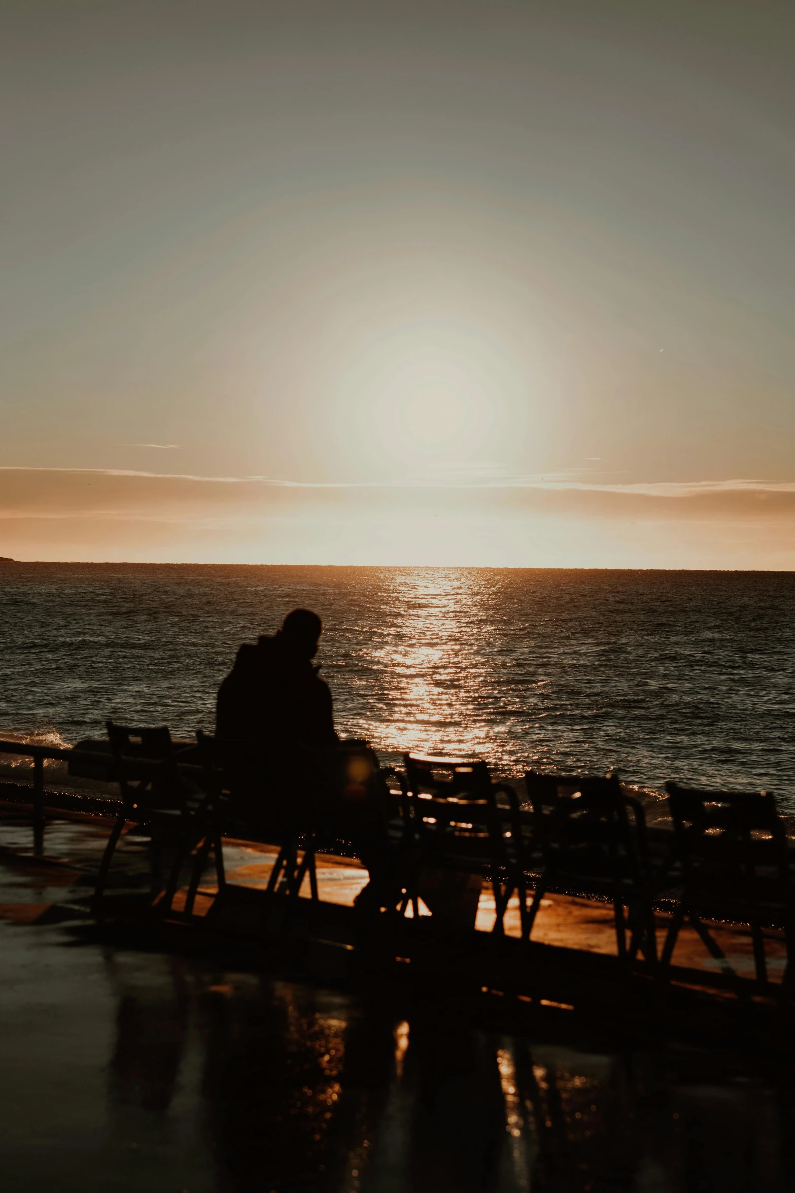 man sitting on bench watching the sunset over the ocean