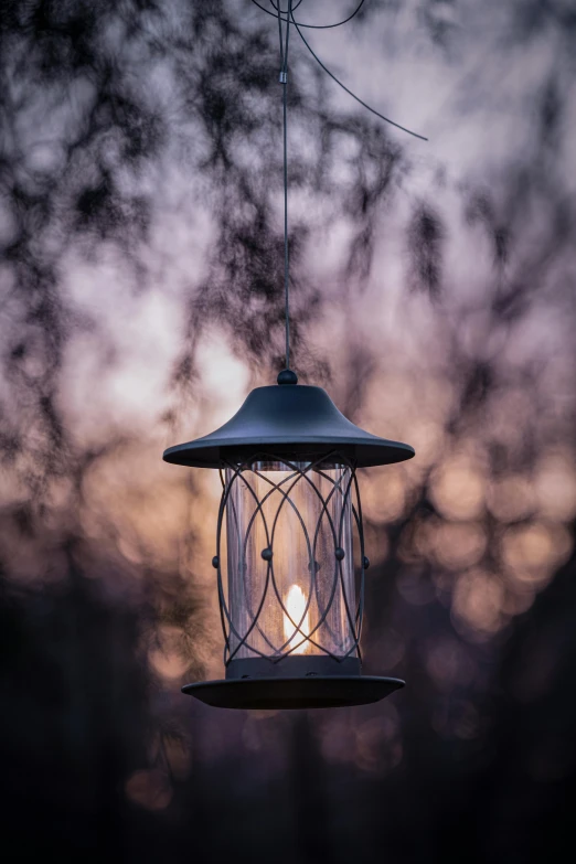 a birdhouse hanging from a wire with a light shining through