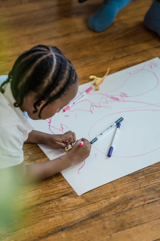 a child is drawing on paper on the floor