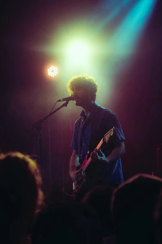 a young man singing into a microphone while playing a guitar