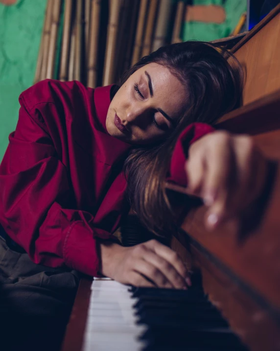 a woman is asleep on top of a piano