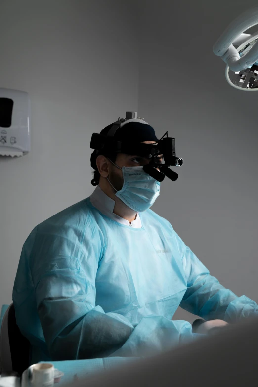 an operating room has the hospital doctor wearing a face mask, a set of surgical gloves and masks on his head