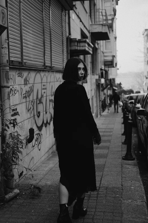 a woman walking down a sidewalk next to a tall building