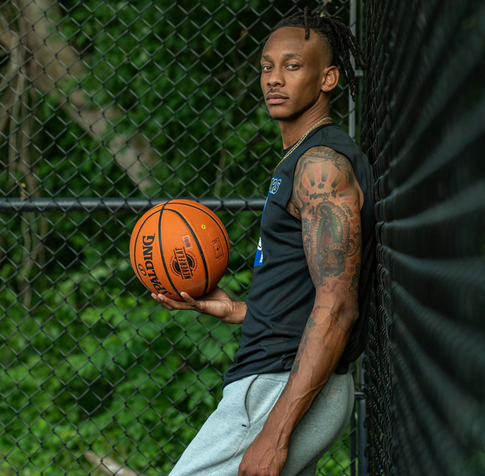 a man with tattoos and a black shirt holding a basketball