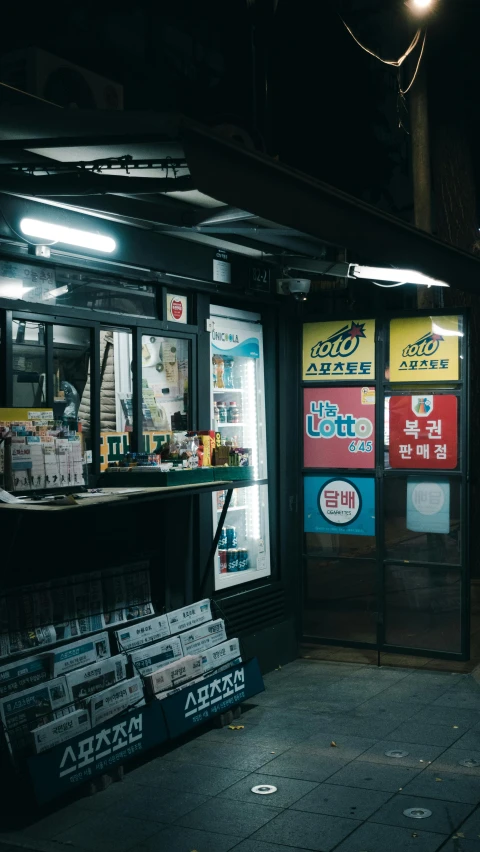 a dark night time scene with two store fronts and some posters