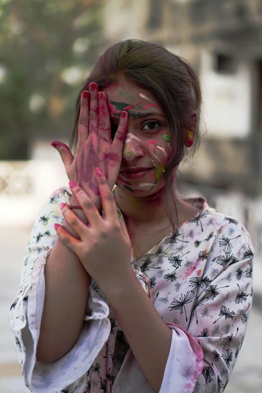 a woman standing while holding up her hands covered in colors