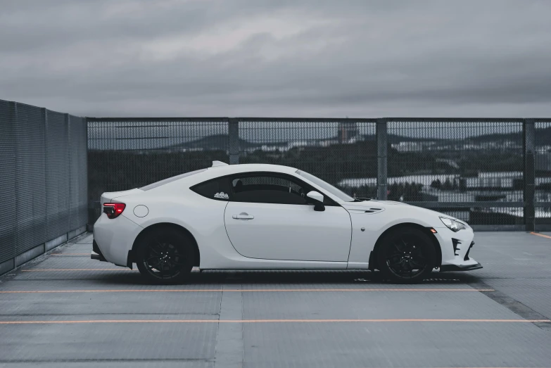 a white car with black rims in an empty parking lot