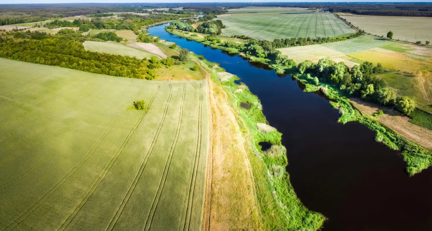 an aerial s of a large river surrounded by fields and trees