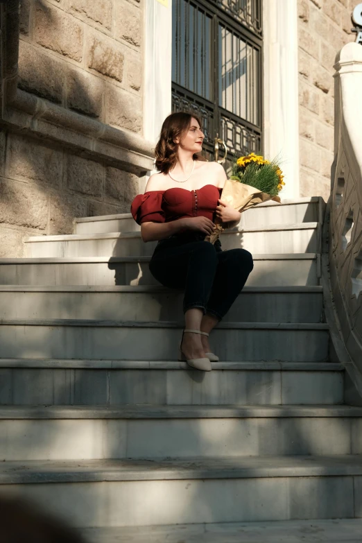 a woman sitting on some stairs holding flowers