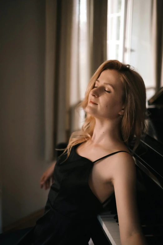 a beautiful woman sitting at a piano posing for the camera