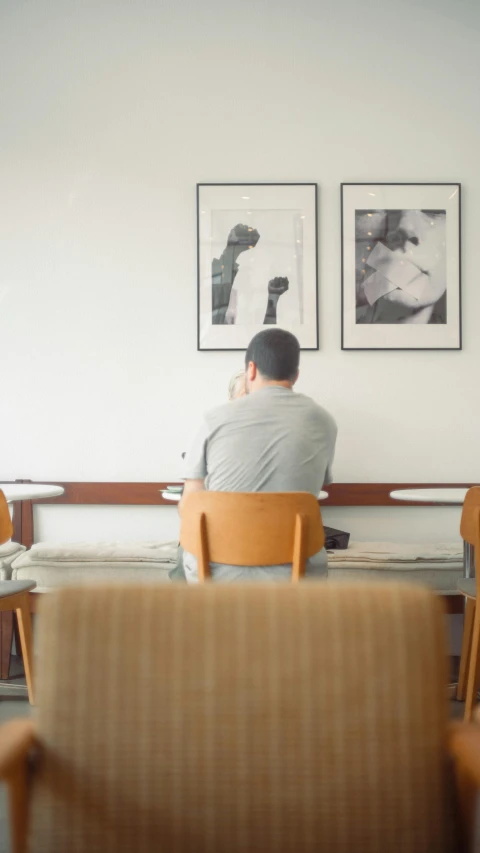 man sitting in a chair staring at paintings on the wall