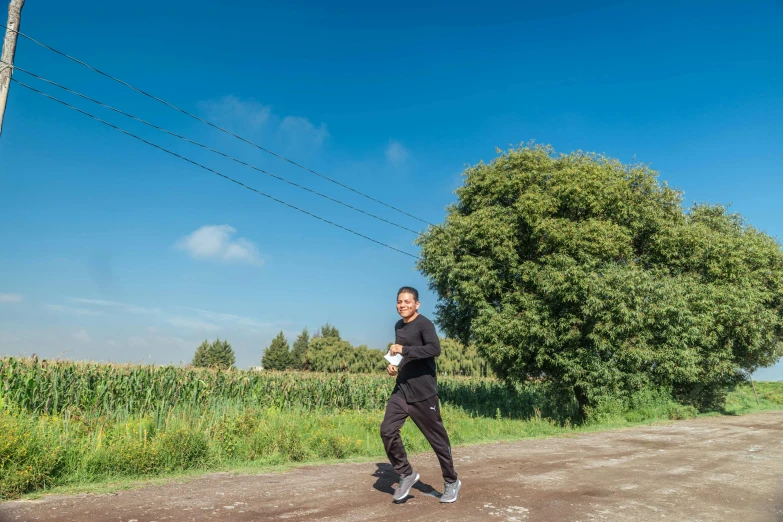 a man in a wet suit stands on a dirt road while running with his hands in his pockets