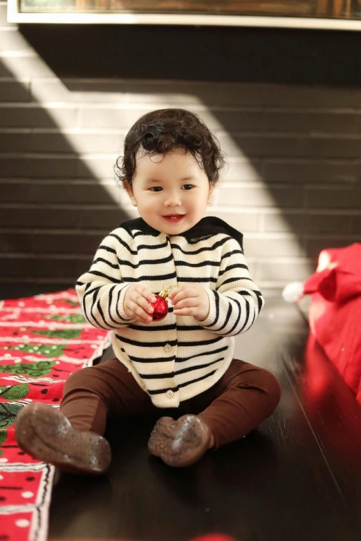 a baby girl is sitting on the floor in a black and white  shirt