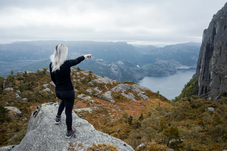 a person on a rock pointing to the valley below