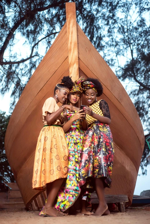 four women in african costumes stand around a boat