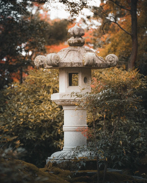 a white stone lantern in front of trees