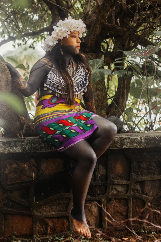 a woman in an native garb sits on a wall