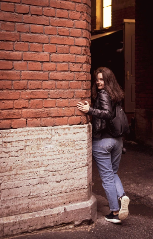 a woman leaning against a wall, arms tucked around a corner