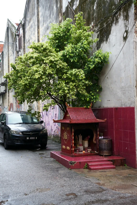 a small shrine under a tree on the side of a street