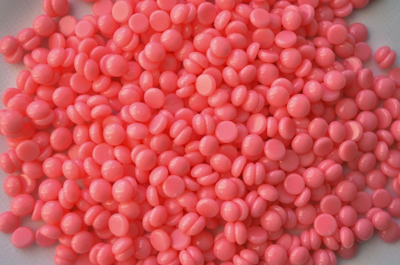 an unpeeled pile of pink gumballs on a white surface