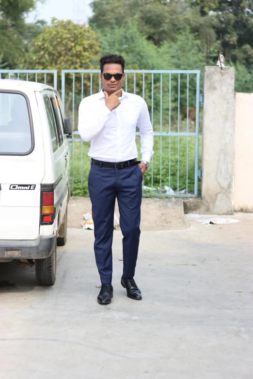 a young man stands next to his van with his hand on his chest