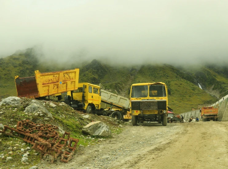 two trucks parked on the side of a dirt road