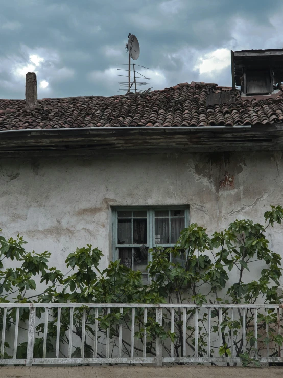 an old white house with vines and a wind vane on the roof