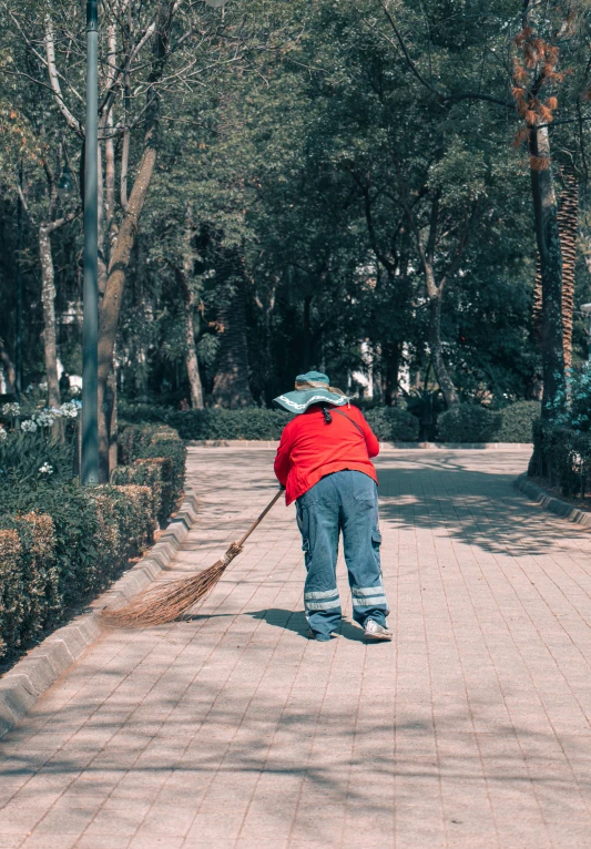 a man sweeping his driveway in the park