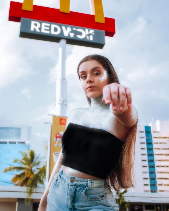 a woman pointing a finger at the camera with a mcdonalds sign in the background