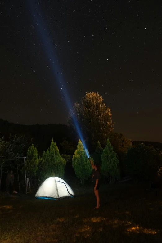 a person standing in front of a tent under the stars
