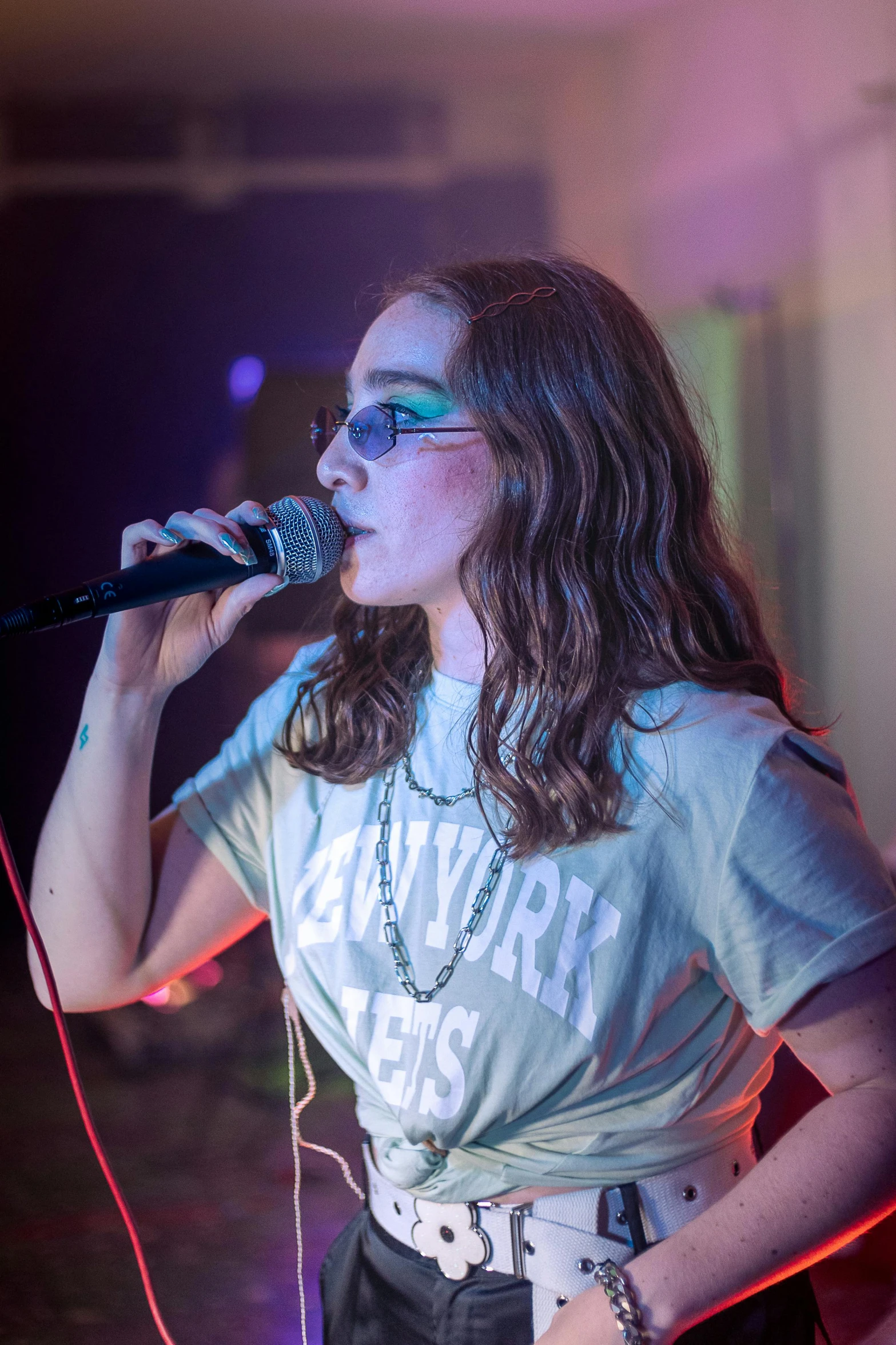 a woman on stage with a microphone up to her ear