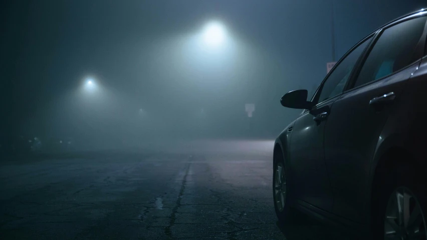 a car parked on a road with fog in the night