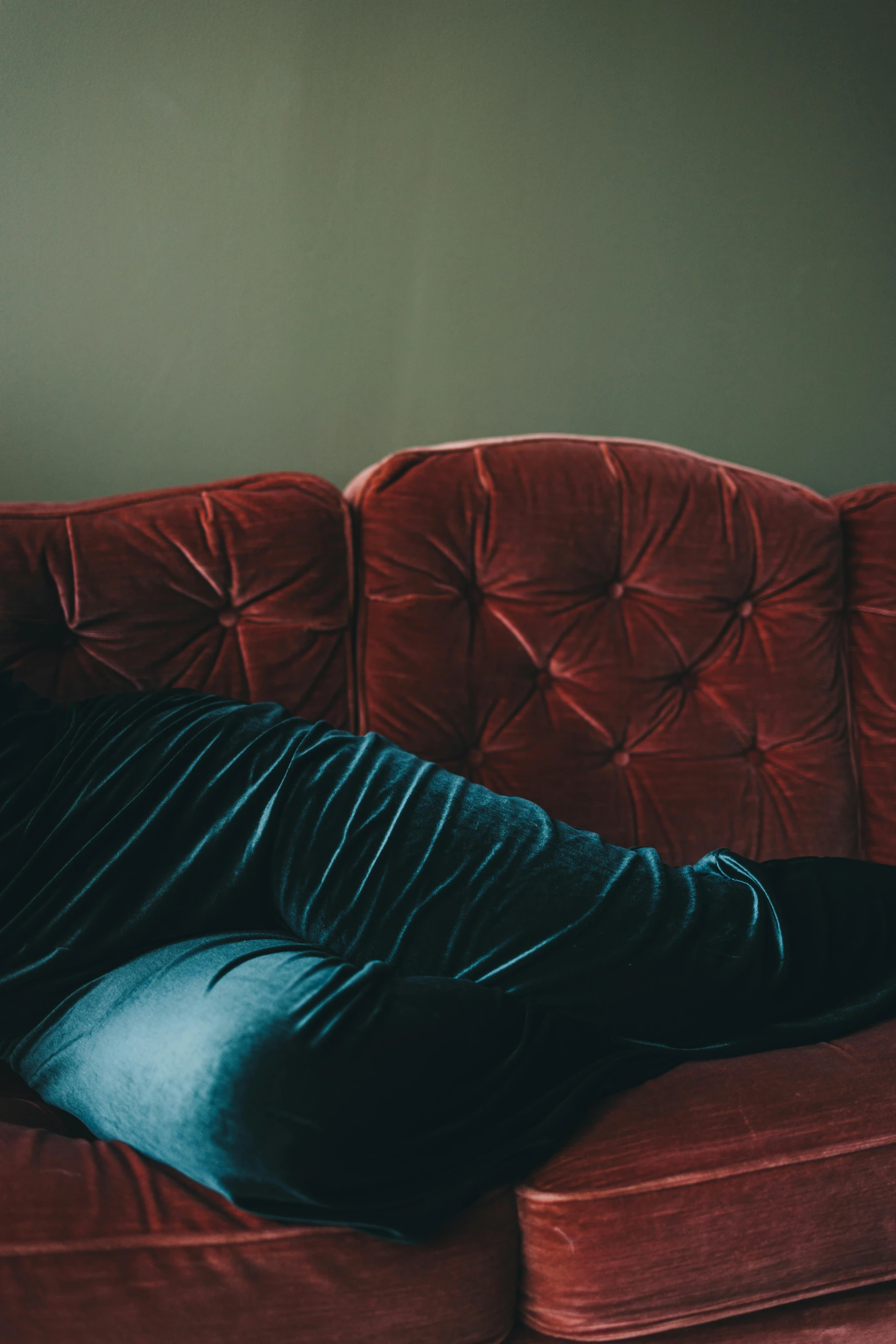 man laying on red couch in room with green wall