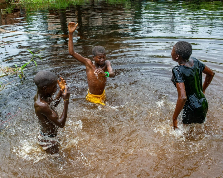 three boys in the water, with arms outstretched