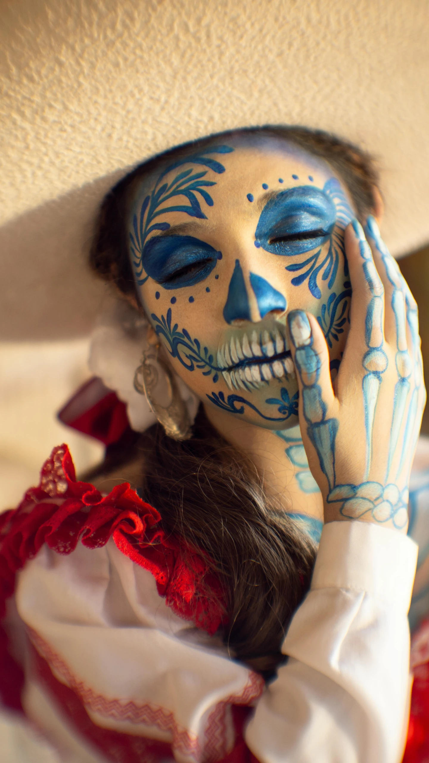 the woman in the skeleton painted face has her hands near her face