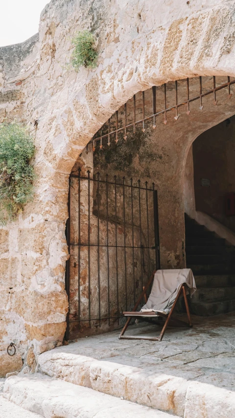 an open doorway with a lawn chair and a stone wall